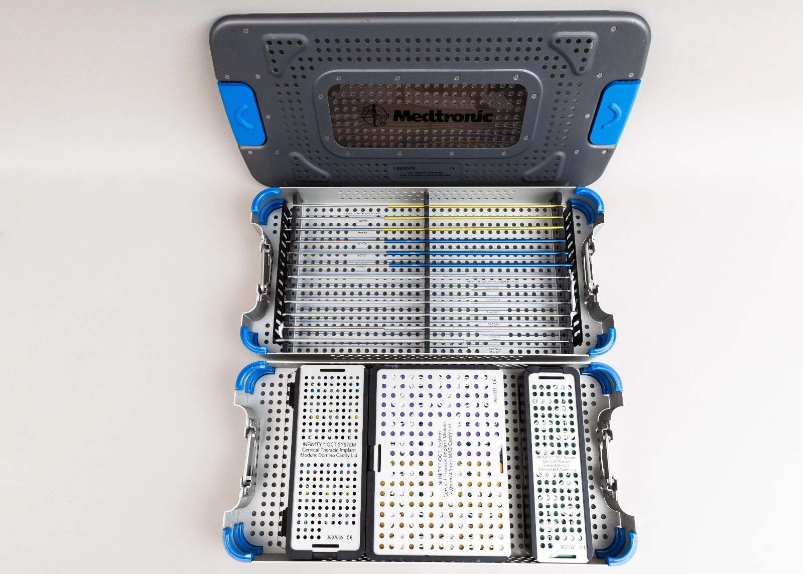 Medtronic INFINITY OCT occipitocervical thoracic implant set with titanium tapered rods, multi-axial screw caddies, and domino connector modules in sterilization case.